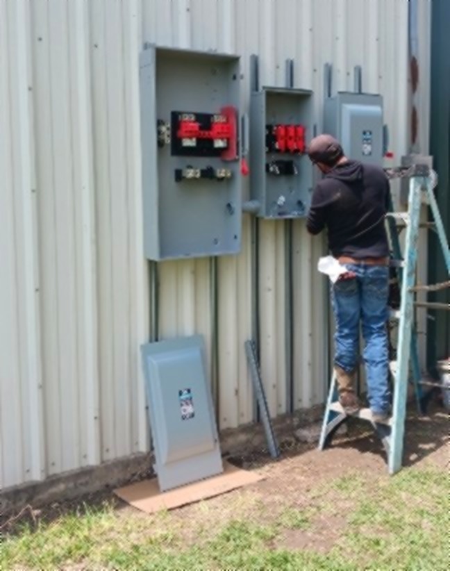 SCI Electrical electrician wiring fused disconnects on a metal building in South Texas